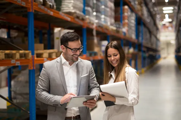 Two professionals coordinate logistics operations in a distribution center, showing how Customs brokers efficiently manage customs documentation.